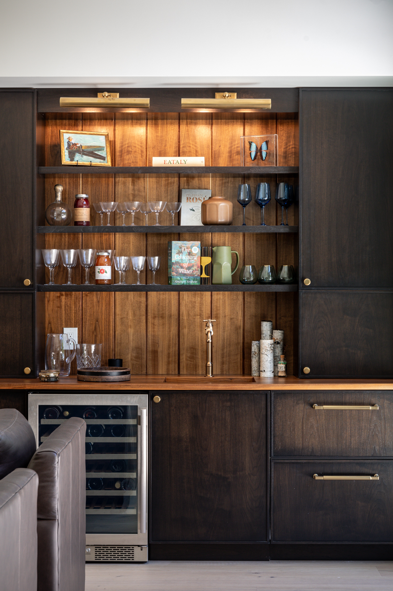 Walnut built-in bar with lit open shelving, glassware and a wine fridge